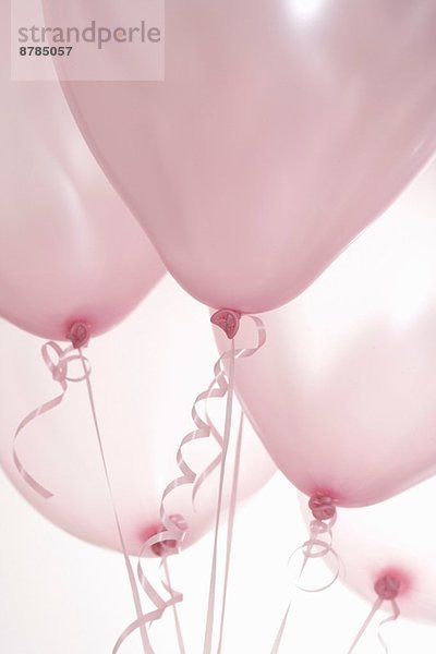 Stilleben von fünf rosa Luftballons auf Bändern