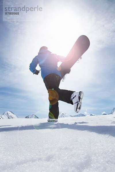 Erwachsener Mann  der sein Snowboard bergauf trägt  Obergurgl  Österreich
