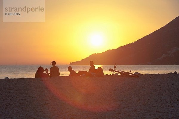 Kleine Gruppe von Leuten  die den Sonnenuntergang am Strand beobachten  Vigan  Kroatien