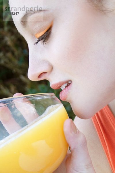 Nahaufnahme einer jungen Frau mit einem Glas Orangensaft