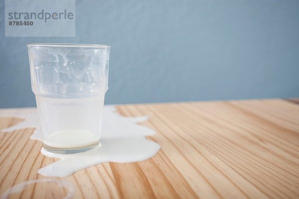 Glas verschüttete Milch auf dem Tisch