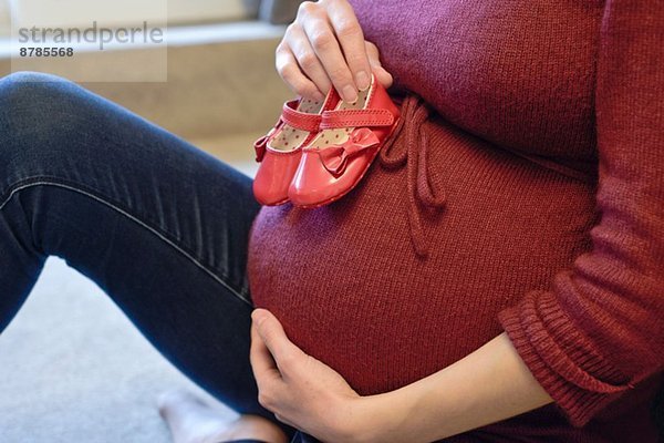 Schwangere Frau mit Babyschuhen an der Beule