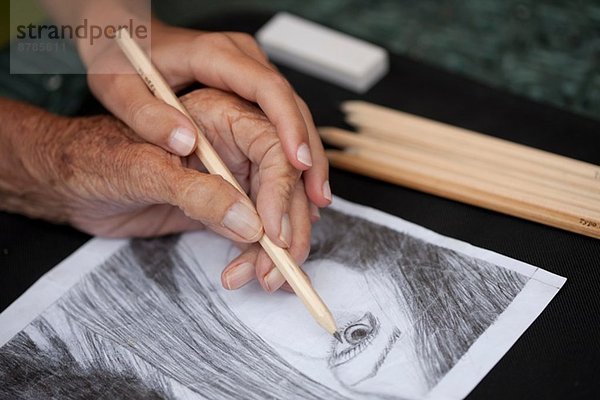 Nahaufnahme der Hand einer älteren Frau  die eine Bleistiftzeichnung macht.