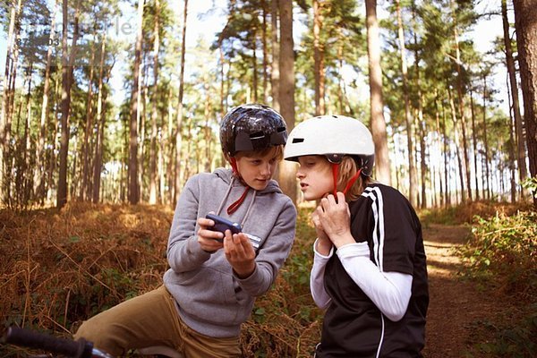 Zwillingsbrüder auf BMX-Bikes im Wald suchen Smartphone