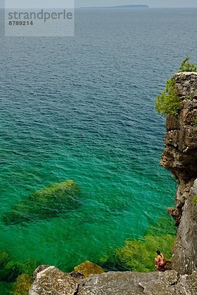 Mittlere erwachsene Frau kauernd auf Felsen an der Küste  Toronto  Ontario  Kanada