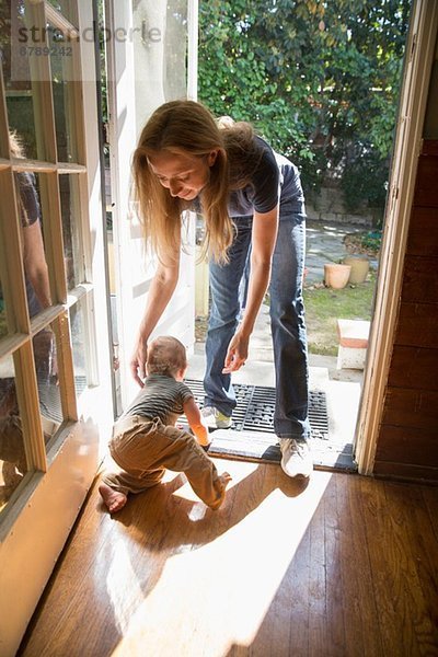 Mutter beugt sich  um Baby zu tragen