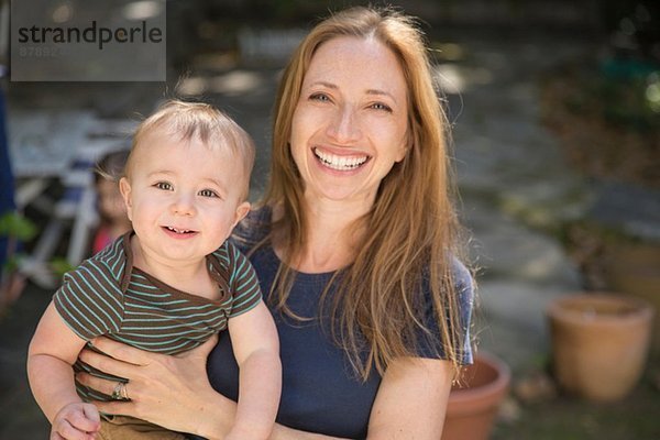 Mutter trägt Baby im Garten