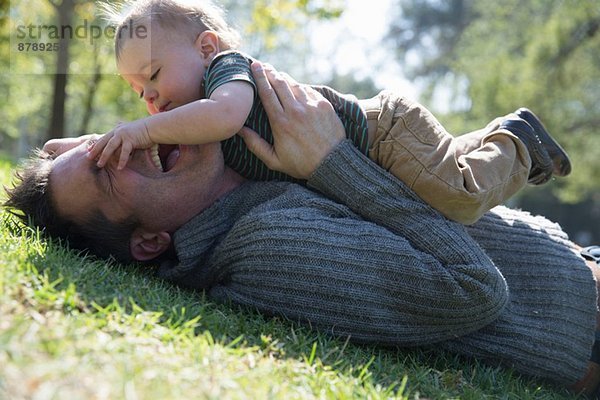 Vater und Sohn spielen auf Rasen