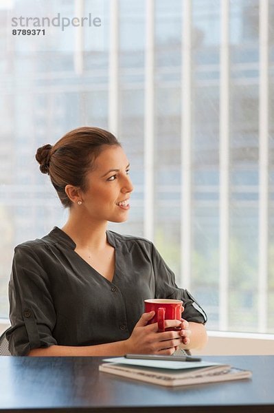 Junge Geschäftsfrau bei einer Kaffeepause im Büro