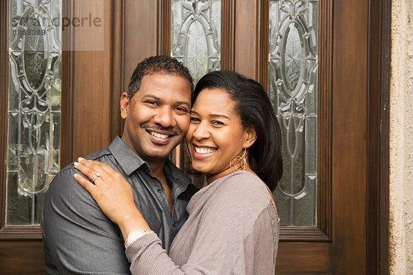 Porträt des glücklichen mittleren Erwachsenenpaares vor der Haustür