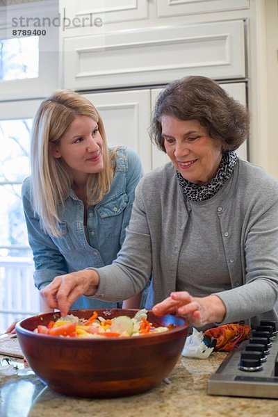Seniorin und Enkelin bereiten Salatschüssel vor