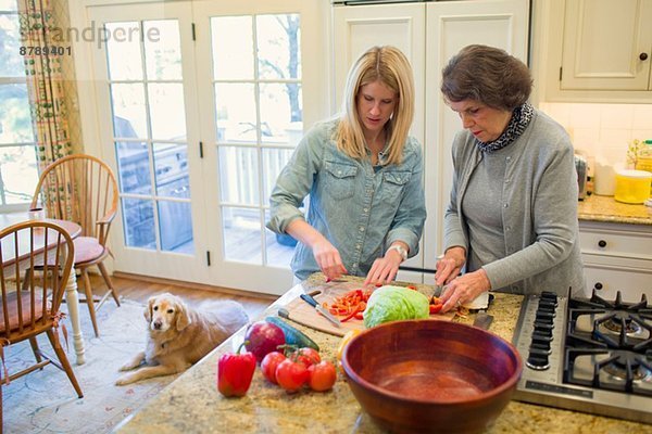 Seniorin und Enkelin hacken Gemüse für Salatschüssel