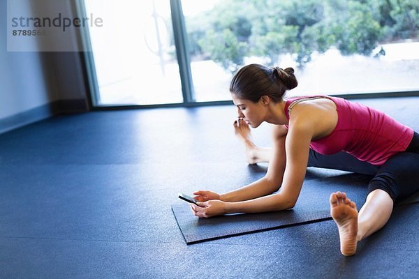 Junge Frau in Yogastellung mit dem Handy