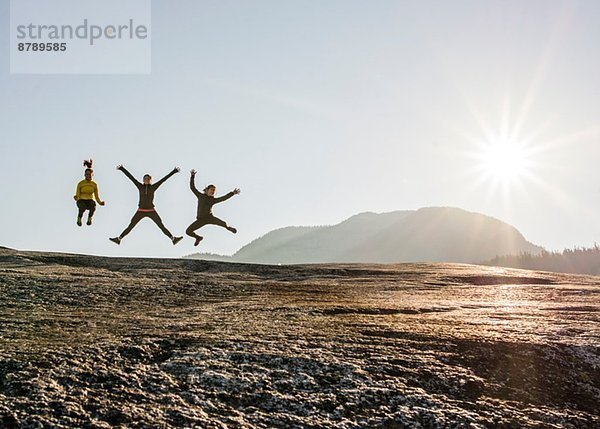 Drei junge Wanderinnen springen in der Luft auf dem Felsen  Squamish  British Columbia  Kanada