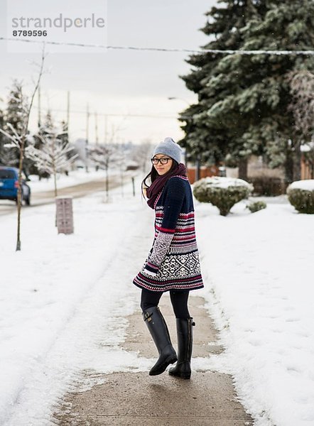 Junge Frau geht die schneebedeckte Straße hinunter