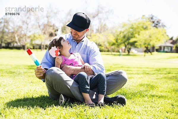 Mittlerer Erwachsener Mann und Tochter essen Eislutscher im Park