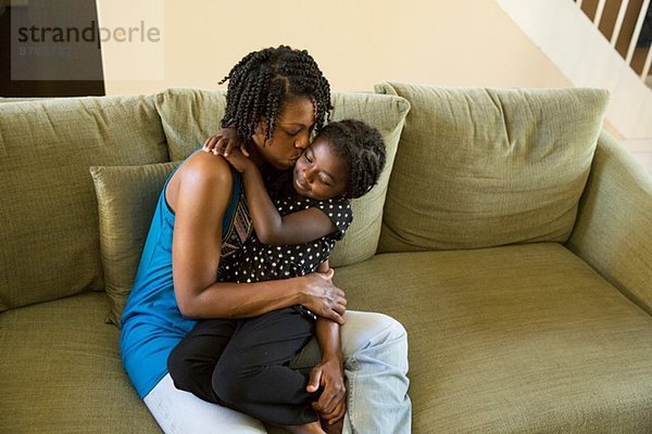 Reife Frau und Tochter umarmend auf dem Sofa