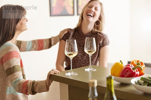 Mittlere erwachsene weibliche Freunde  die in der Küche lachen.