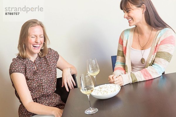 Mittlere erwachsene Freundinnen trinken Weißwein und Lachen