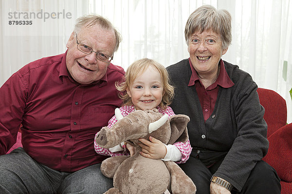 Großeltern und die 3-jährige Enkeltochter mit einem Stofftier