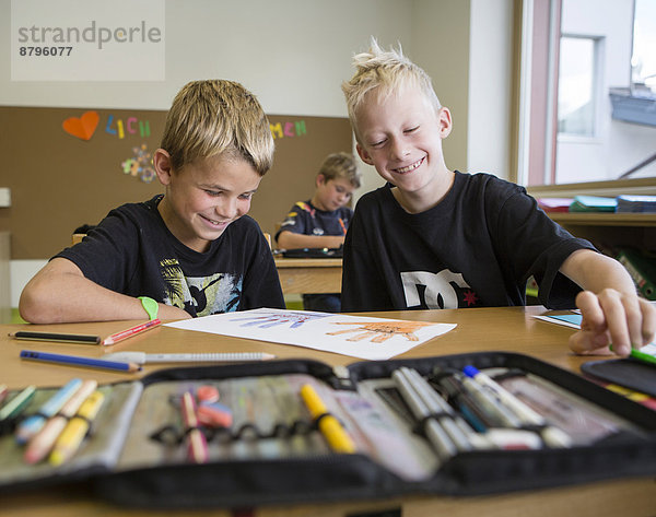 Kinder sitzen lachend in einer Volksschulklasse im Zeichenunterricht  Reith im Alpbachtal  Bezirk Kufstein  Tirol  Österreich