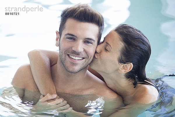 Paar entspannt sich zusammen im Pool  Frau küsst Männerwange