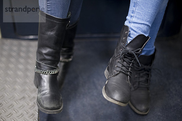 Frauen sitzen zusammen in der U-Bahn  Nahaufnahme der Stiefel