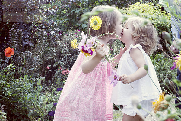Kleines Mädchen  das seine kleine Schwester im Freien küsst.