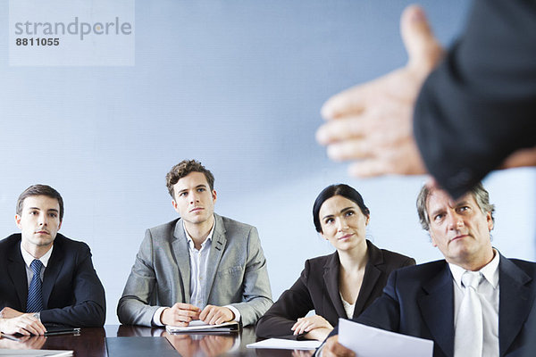 Geschäftspartner hören zu  wenn ein Kollege während der Besprechung eine Präsentation hält.