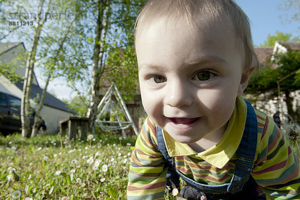 Baby krabbelt im Gras  lächelt fröhlich  Portrait