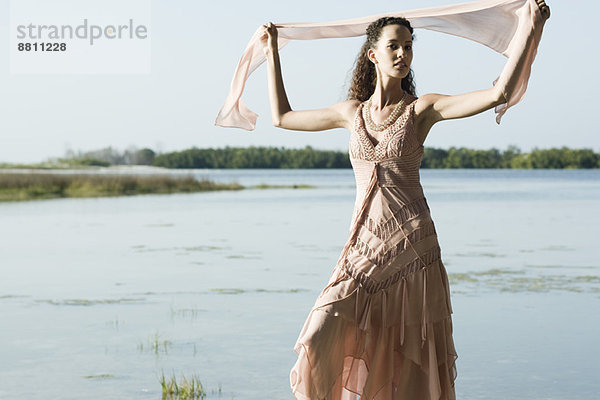 Junge Frau im Kleid  Schal hochhaltend  See im Hintergrund