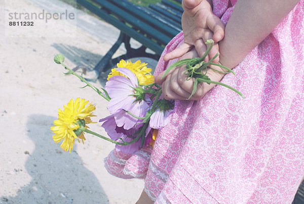 Kleines Mädchen mit Blumen auf dem Rücken