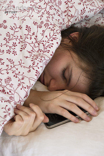 Frau schläft im Bett mit Smartphone in der Hand