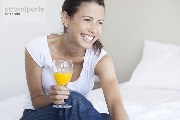 Junge Frau beginnt ihren Tag mit einem Glas Orangensaft