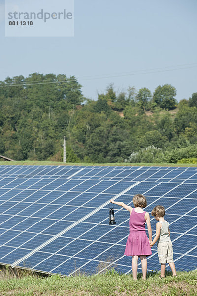 Kinder stehen zusammen vor Sonnenkollektoren  Mädchen mit altmodischer Laterne