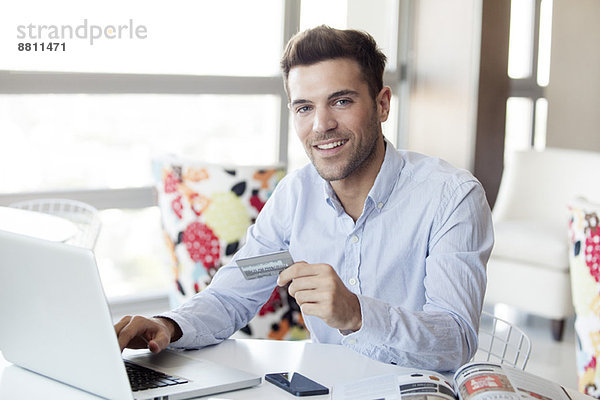 Mann  der sich auf einen Online-Einkauf mit Kreditkarte vorbereitet.
