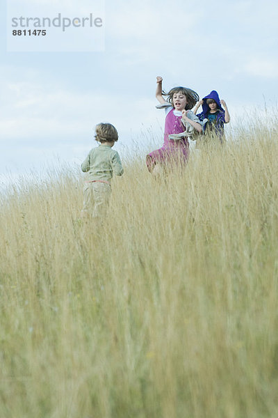 Kinder beim Spielen im hohen Gras am Hang