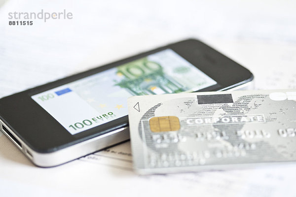 Kreditkarte auf dem Smartphone mit Hundert-Euro-Banknote