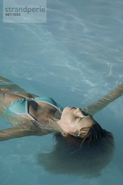 Junge Frau im Schwimmbad schwimmend  Augen geschlossen