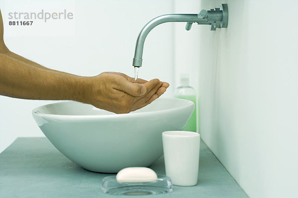 Männerhände unter fließendem Wasser im Waschbecken  Seitenansicht