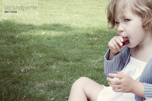 Kleines Mädchen isst süßen Snack im Freien