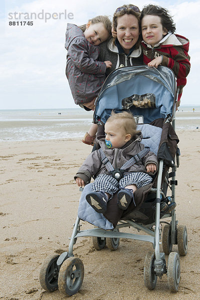 Mutter mit drei Kindern am Strand