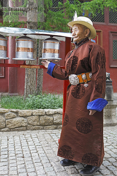 Alter Mann im traditionellen Deel dreht Gebetsmühlen im buddhistischen Gandan-Kloster  Ulaanbaatar  Mongolei
