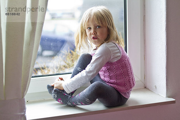 Mädchen sitzt auf der Fensterbank