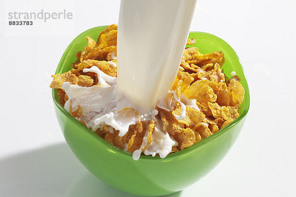 Milch in grüne Schale mit Cornflakes gießen