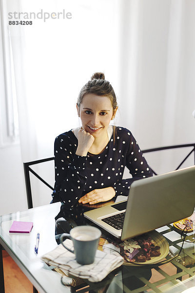 Junge Frau bei der Arbeit mit dem Laptop zu Hause