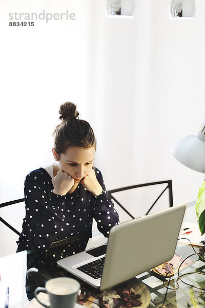 Junge Frau bei der Arbeit mit dem Laptop zu Hause