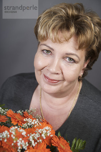 Porträt der glücklichen Frau mit Blumenstrauß