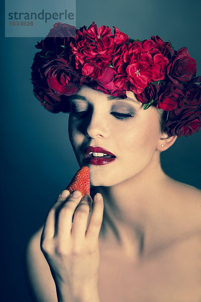 Porträt einer jungen Frau mit roten Blumen und Blick auf Erdbeere