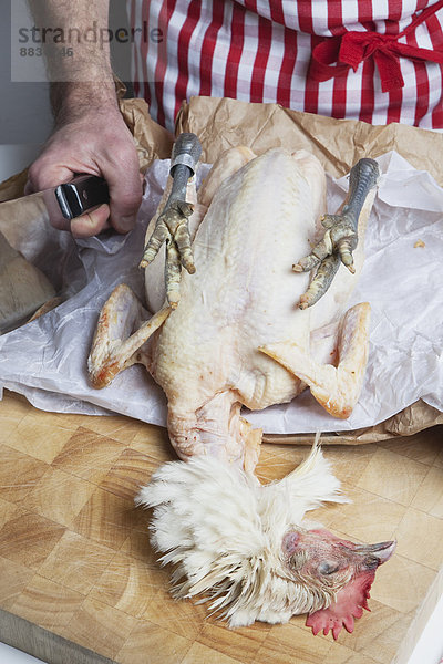 Koch bereitet rohes Bresse-Huhn auf Schneidebrett zu